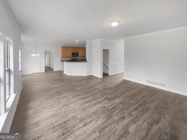 unfurnished living room featuring ornamental molding, dark hardwood / wood-style floors, and a notable chandelier