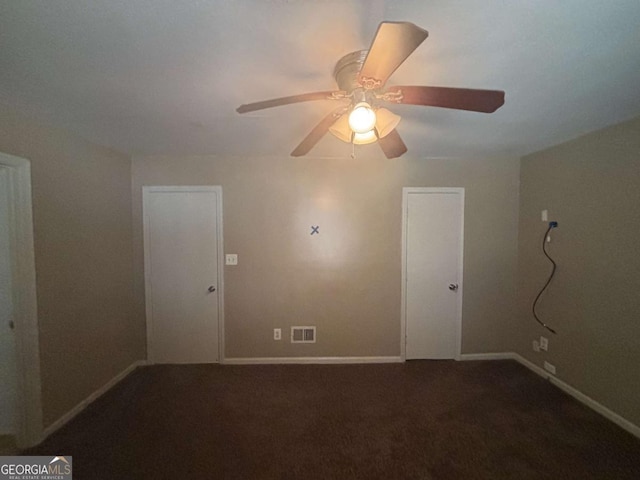 spare room featuring ceiling fan and dark colored carpet