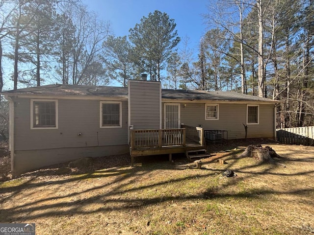 rear view of house featuring a wooden deck and a yard