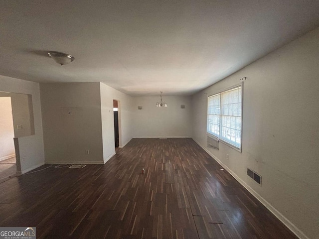 unfurnished living room featuring dark hardwood / wood-style floors and an inviting chandelier