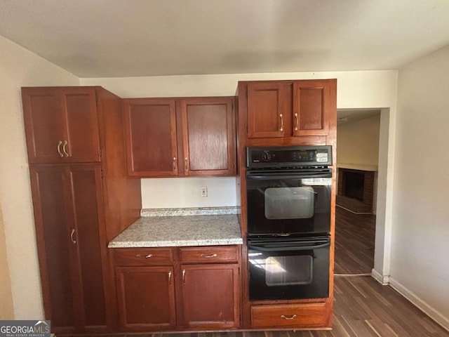 kitchen featuring black double oven and dark hardwood / wood-style flooring