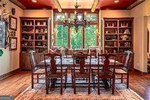 dining room featuring a chandelier, beamed ceiling, wood finished floors, and baseboards