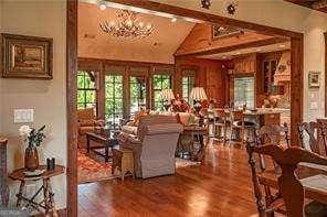 interior space featuring vaulted ceiling with beams, wood finished floors, and a notable chandelier