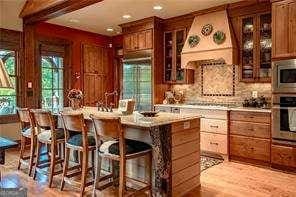 kitchen with light countertops, appliances with stainless steel finishes, custom exhaust hood, and glass insert cabinets