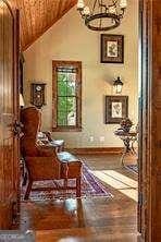 sitting room featuring lofted ceiling, wood finished floors, and a notable chandelier