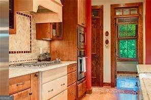 kitchen with premium range hood, appliances with stainless steel finishes, brown cabinets, and backsplash