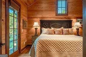 bedroom with lofted ceiling, a fireplace, and wooden walls