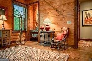 sitting room with wood walls, baseboards, and wood finished floors