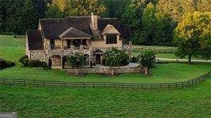 view of front of home with a front lawn, a rural view, and a chimney