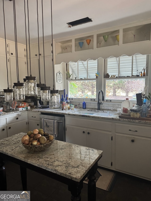 kitchen with sink, white cabinetry, light stone counters, dishwasher, and a kitchen island