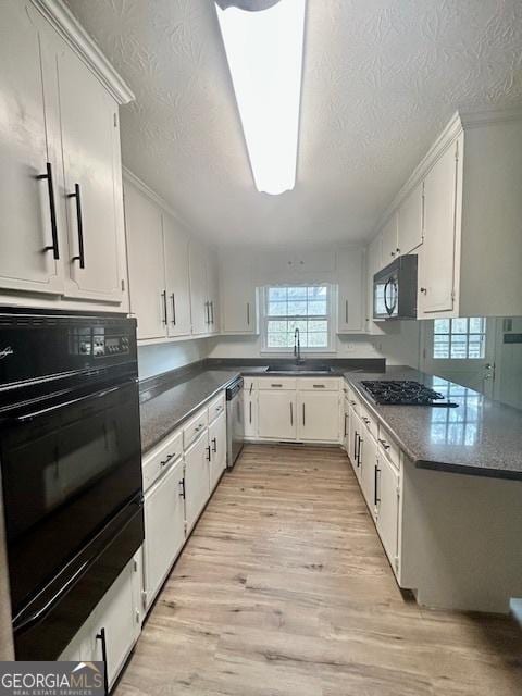 kitchen with white cabinetry, sink, light hardwood / wood-style flooring, and black appliances