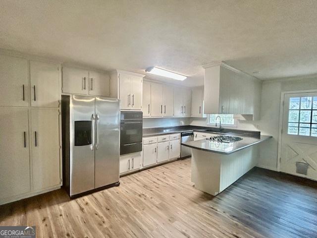 kitchen featuring sink, white cabinetry, light hardwood / wood-style flooring, appliances with stainless steel finishes, and kitchen peninsula