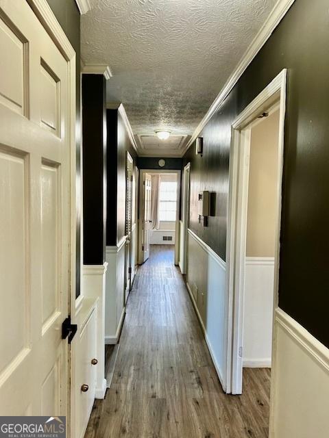 hall with hardwood / wood-style flooring, crown molding, and a textured ceiling