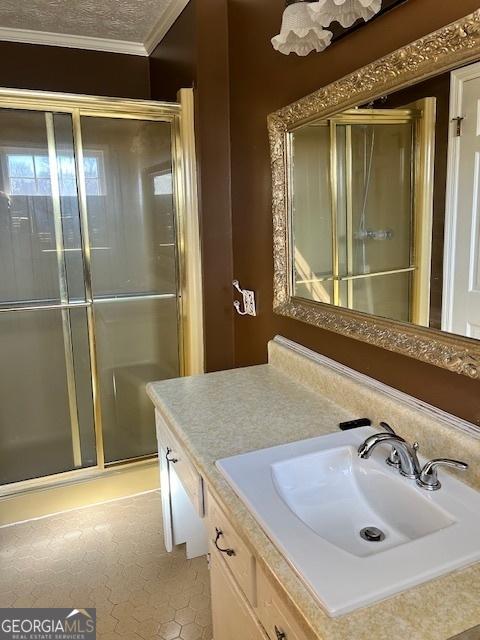 bathroom with crown molding, vanity, a shower with shower door, and a textured ceiling