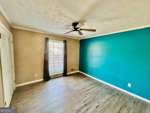 unfurnished bedroom featuring crown molding, light hardwood / wood-style flooring, ceiling fan, a textured ceiling, and a closet