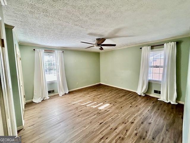 interior space with ornamental molding, plenty of natural light, hardwood / wood-style floors, and ceiling fan