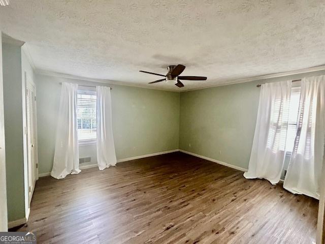 unfurnished room featuring ceiling fan, ornamental molding, dark hardwood / wood-style floors, and a textured ceiling