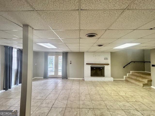 unfurnished living room featuring a drop ceiling, a fireplace, and tile patterned floors