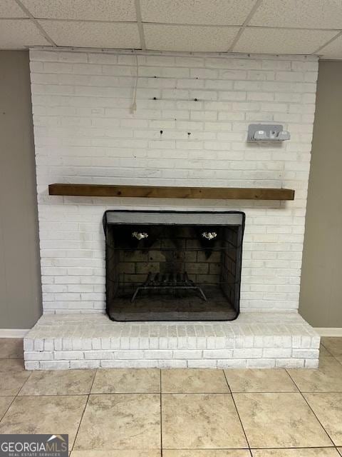 interior details featuring a drop ceiling and a brick fireplace