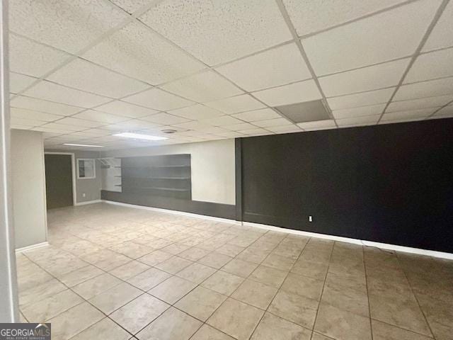 basement with a drop ceiling and light tile patterned floors