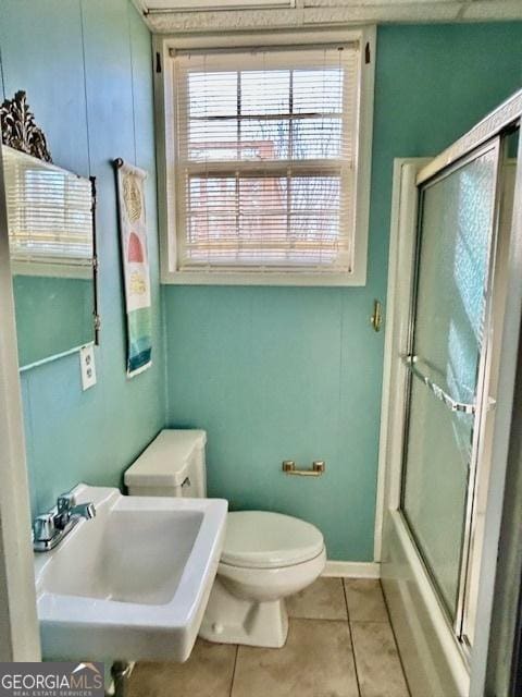 full bathroom featuring toilet, tile patterned floors, combined bath / shower with glass door, and sink