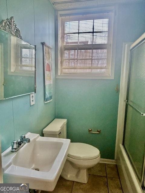 full bathroom with toilet, bath / shower combo with glass door, tile patterned flooring, and sink