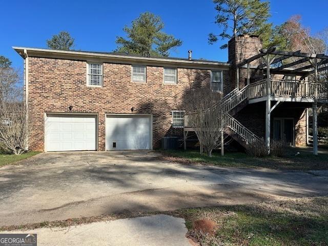 back of house featuring a wooden deck, a garage, and a pergola