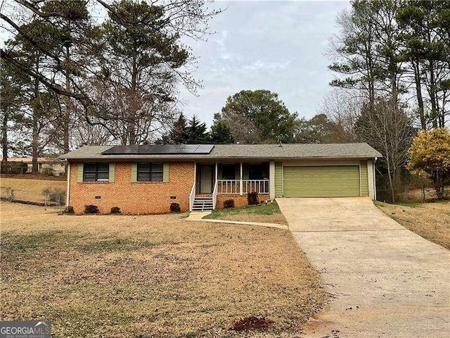 single story home featuring a garage, a front lawn, solar panels, and covered porch