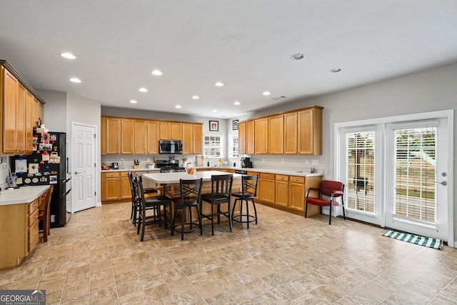 kitchen with black fridge, a center island, a breakfast bar area, and stove