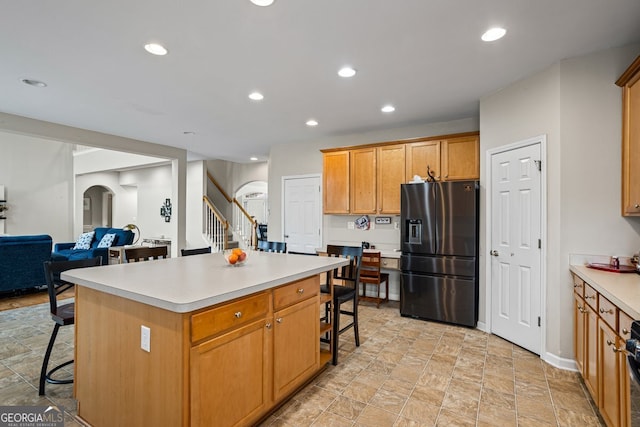 kitchen featuring a center island, a breakfast bar, and fridge with ice dispenser