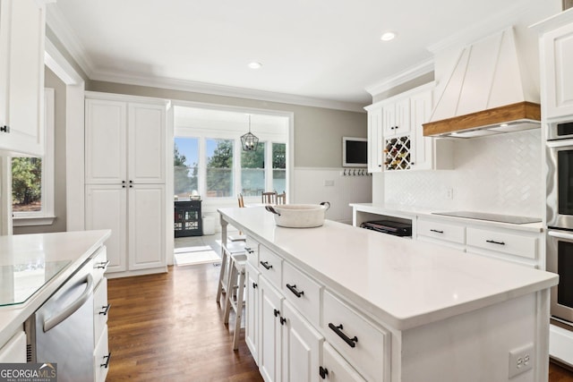 kitchen featuring premium range hood, a kitchen island, white cabinets, black electric stovetop, and crown molding