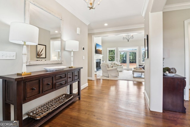 hall with ornamental molding, a notable chandelier, dark hardwood / wood-style flooring, and french doors