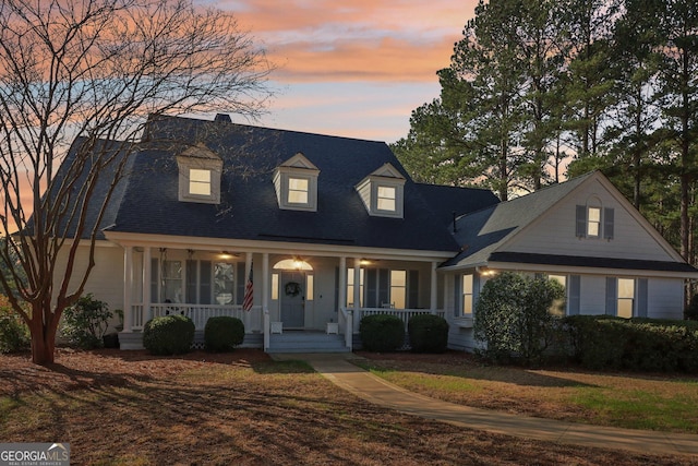 cape cod-style house with covered porch and a lawn