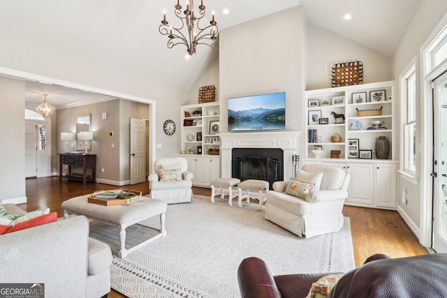 living room featuring light hardwood / wood-style flooring, high vaulted ceiling, and a chandelier