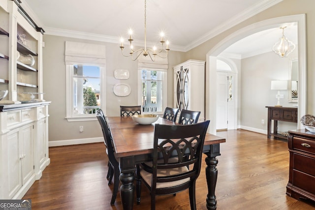 dining space featuring dark wood-type flooring, crown molding, and a chandelier