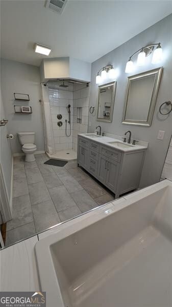 bathroom with vanity, tiled shower, and toilet