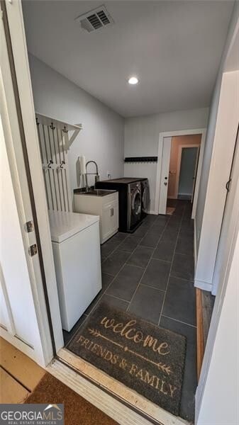 washroom with cabinets, sink, dark tile patterned flooring, and washer / clothes dryer