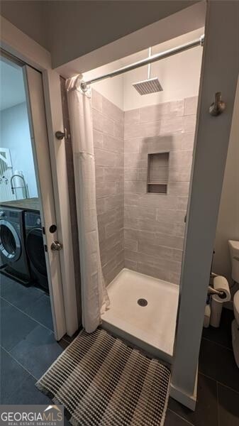 bathroom with a shower with curtain, independent washer and dryer, tile patterned floors, and toilet