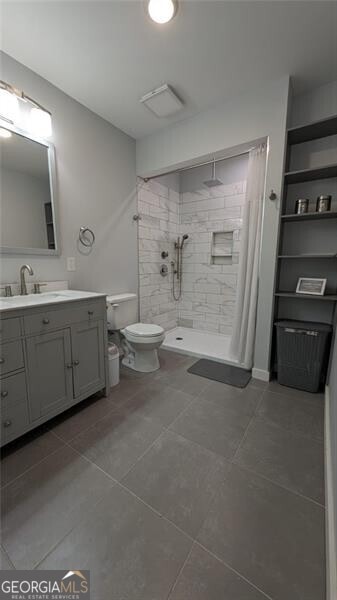 bathroom with vanity, tile patterned floors, toilet, and walk in shower