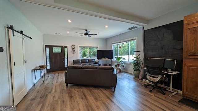 living room with wood-type flooring, a barn door, and ceiling fan