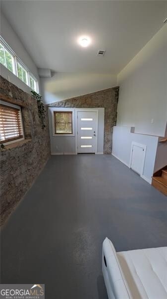 unfurnished living room featuring lofted ceiling and concrete floors