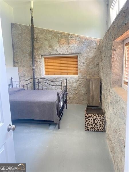 unfurnished bedroom featuring a towering ceiling and concrete floors