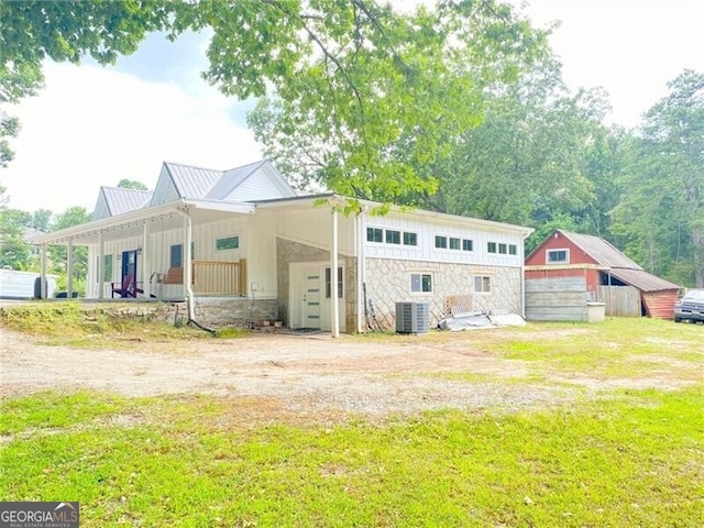 back of property with an outdoor structure, central AC unit, covered porch, and a lawn