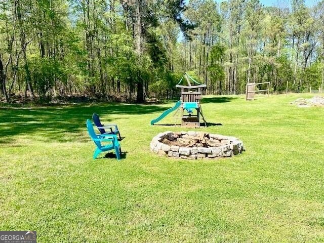 view of property's community featuring a playground, a lawn, and an outdoor fire pit