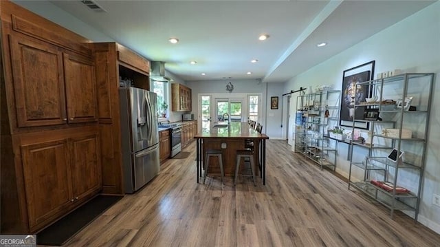 kitchen featuring a center island, a kitchen breakfast bar, hardwood / wood-style flooring, stainless steel appliances, and a barn door