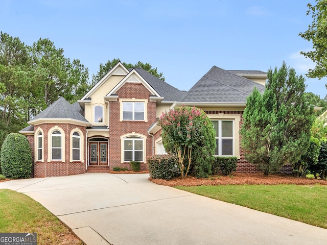 view of front facade featuring concrete driveway, french doors, roof with shingles, and brick siding