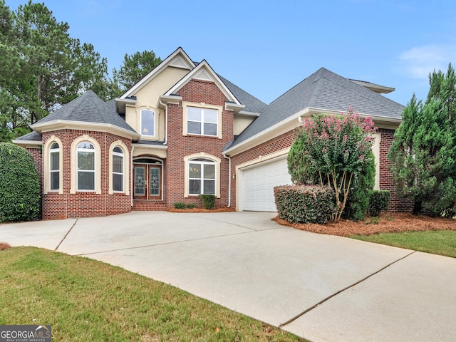 traditional-style home featuring french doors, brick siding, roof with shingles, a garage, and driveway