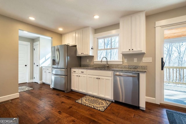 kitchen with dark hardwood / wood-style floors, white cabinetry, sink, light stone counters, and stainless steel appliances