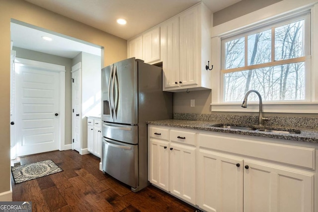 kitchen with stone counters, sink, white cabinets, and stainless steel fridge with ice dispenser