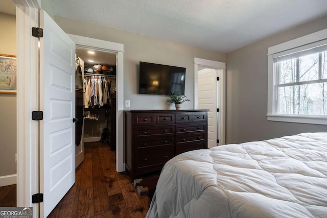 bedroom featuring a spacious closet, dark hardwood / wood-style floors, a closet, and a textured ceiling